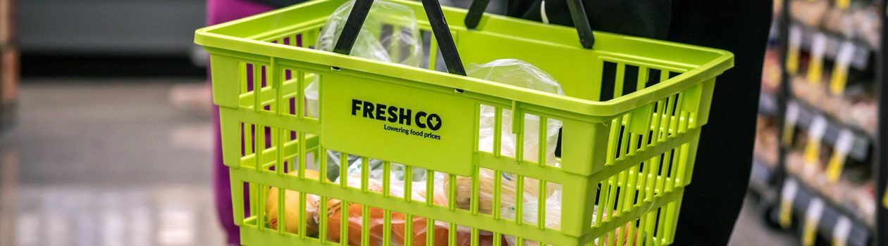 Customer holding filled Freshco basket in-store